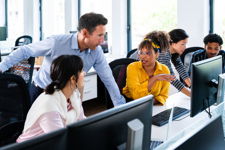Diverse team of business professionals collaborating and working together on computer projects in a...