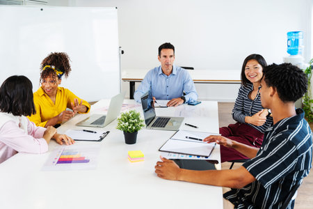 Diverse team of professionals collaborating around a table, engaging in a productive meeting to...