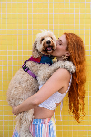 Redhead woman embraces and kisses her happy doodle dog, celebrating the strong bond and friendship...