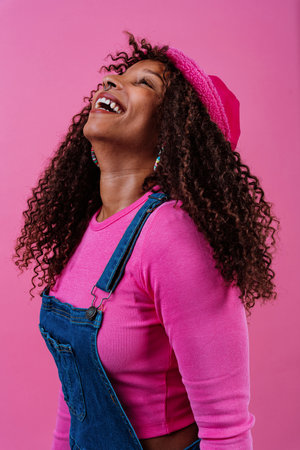 Fashion portrait of a cheerful young woman with curly hair, wearing a pink bucket hat, pink...