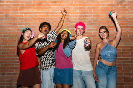Multiethnic group of young friends having fun on the streets in the night - Stylish cool multiracial people wearing stylish clothing hanging out before party in a disco clubの写真素材