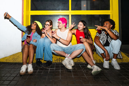 Multiethnic group of young friends having fun on the streets in the night - Stylish cool multiracial people wearing stylish clothing hanging out before partyの写真素材