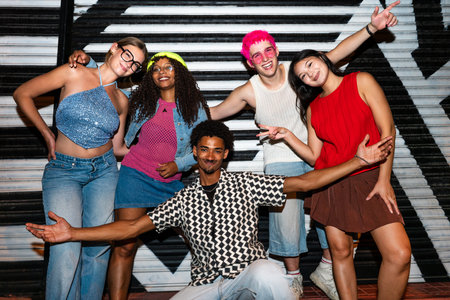 Multiethnic group of young friends having fun on the streets in the night - Stylish cool multiracial people wearing stylish clothing hanging out before party in a disco clubの写真素材