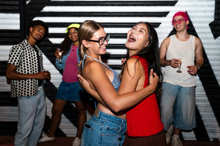 Multiethnic group of young friends having fun on the streets in the night - Stylish cool multiracial people wearing stylish clothing hanging out before party in a disco clubの写真素材