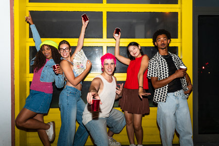 Multiethnic group of young friends having fun on the streets in the night - Stylish cool multiracial people wearing stylish clothing hanging out before party in a disco clubの写真素材