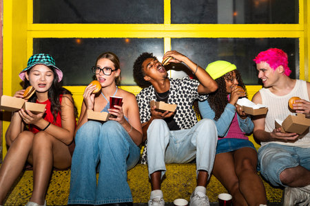 Multiethnic group of young friends having fun on the streets in the night - Stylish cool multiracial people wearing stylish clothing hanging out before party in a disco clubの写真素材