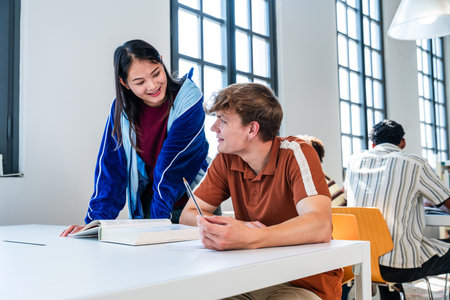 Multiethnic group of young students meeting at the library - diverse students collaborating on a...