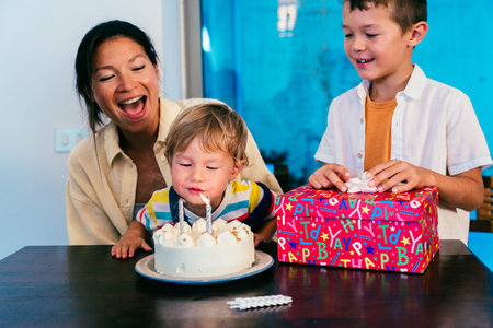 Asian family at home - asian mother and her two children celebrating a birthday at home. Little boy...