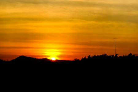 Brilliant and colorful orange sunset with silhouette of mountain range and incredible cloud formationsの写真素材