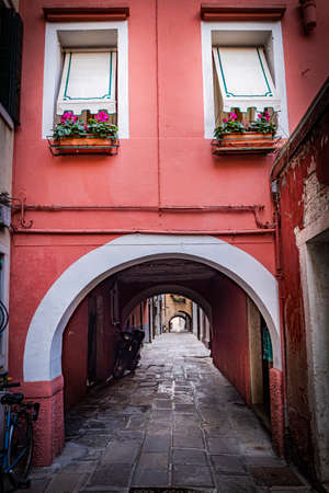 romantic and characteristic Italian colorful street with multi colored houses in Chioggia near Venice, with sunset lightの写真素材