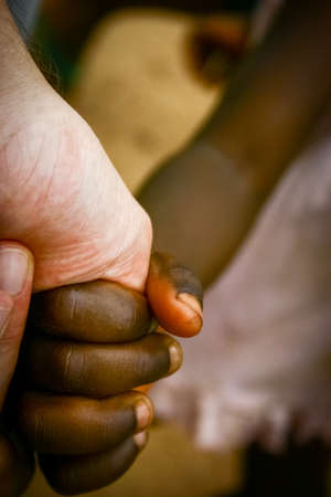 White adult hand holding black children's handsの写真素材