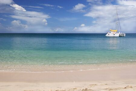 A catamaran anchored out along a tropical beach.の写真素材