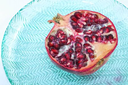 Sliced pomegranate on a blue glass plate.の写真素材