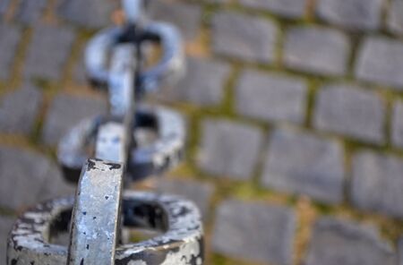 Rusty chain links over cobble stone side walkの写真素材