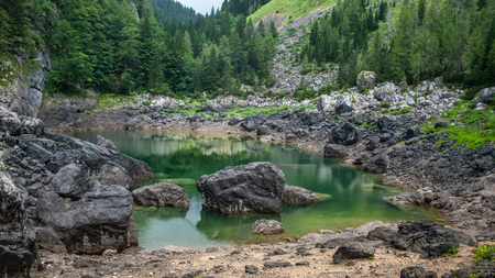 Beautiful view of the rock on the shore of a green lake with the rainbow above.Julian Alps, Slovenia.の写真素材