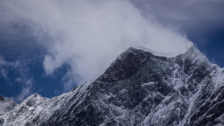 Panoramic view of a mountain peak covered with a snow on the top. Blowing snow and clouds blending above peakSummer in the Pennine Alps, Valle d'Aosta, Italy, Europe.の写真素材