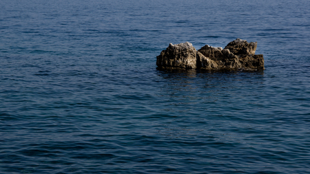 Close up view of one gray rock surrounded by blue sea. Use for background. Autumn in Opatija, Croatia, Europe.の写真素材