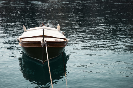 Landscape view of one brown wooden boat tied in the front. Surrounded with a blue sea with small...