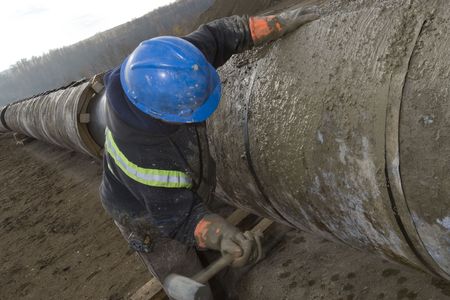 A pipeline construction worker hammering on a pipeの写真素材