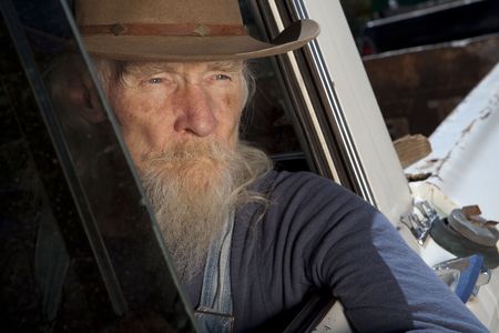 An elderly man with a white beard driving a pickup truck and staring out the windowの写真素材