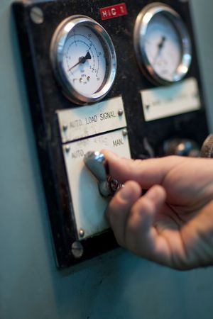 The hand of an operator working controls in an industrial factoryの写真素材