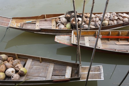 Traditional boats in a floating market are moored in a river. They are filled with harvested fruit. Horizontal shot.の写真素材