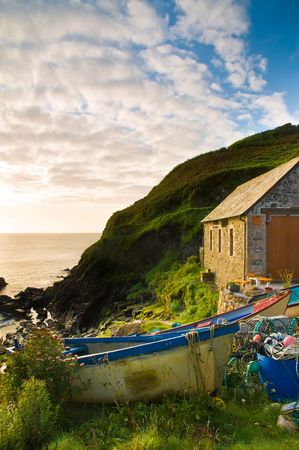 Colourful fishing boats and lobster pots on the slipway to a small Cornish fishing village in England, UK.の写真素材