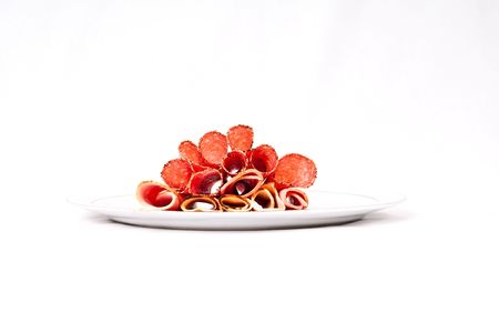 A platter of cooked meat containing ham, chicken and salami.