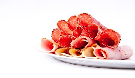 A platter of three cooked meats containing ham, chicken and salami.の写真素材