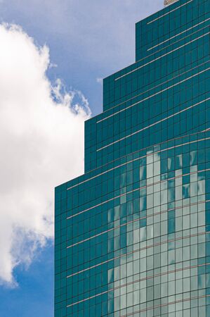 Cloud reflection on green glass building under the blue skyの写真素材