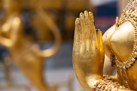 Close up photo of wai the traditional thai greeting method appeared on a gold painted statue in Wat Prakaew Bangkok Thailandの写真素材