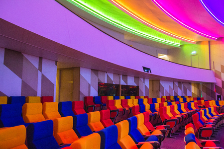 Empty modern auditorium with all colorful lights on.Spacious auditorium with rows of chairs and stairsのeditorial素材