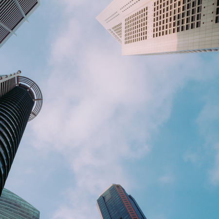 Low angle shot of modern glass city buildings with sky background.Common modern business...