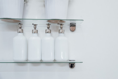 Bathroom soap dispenser and pot on shelf with white background of negative space horizontal.White ceramic bottles with liquid soap or shower gel at hotel.の写真素材