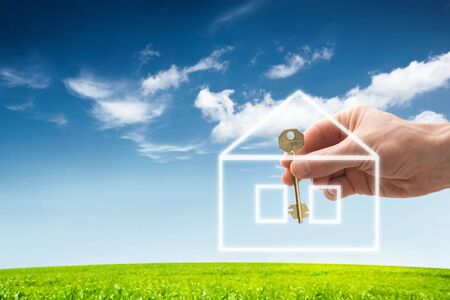 hand holding a house key with a new homeの写真素材