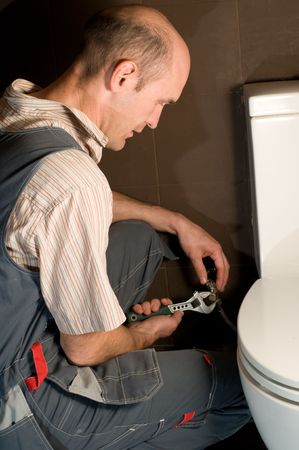plumber using a pipe wrench to repair a sinkの写真素材