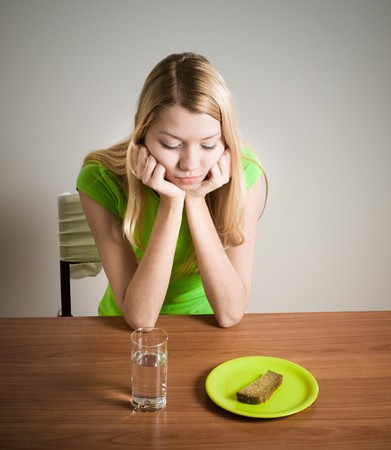 girl sitting at table with bread and glass of waterの写真素材