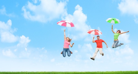 young friends jumping with umbrellasの写真素材