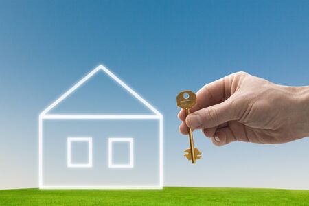 hand holding a house key with a new homeの写真素材