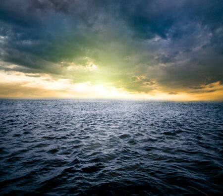 a sunrise over dark water of oceanの写真素材