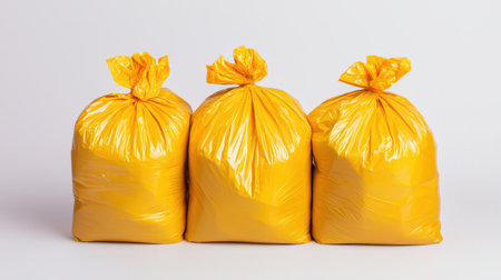 Bright Yellow Garbage Bags Filled with Waste on a Clean Background for Recycling or Environmental Awareness Conceptsの素材