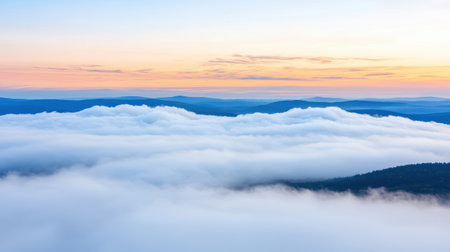 Serene View of Rolling Clouds Against a Vibrant Sunrise Over Misty Mountains in Nature's Tranquil Landscape During Early Morning Hoursの素材