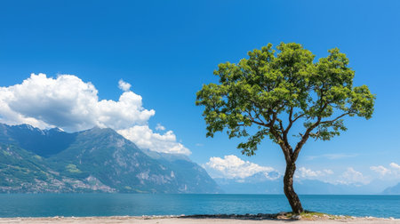Serene Landscape with Isolated Tree near Calm Lake under Clear Blue Sky and Majestic Mountains in the Background on a Bright Sunny Dayの素材