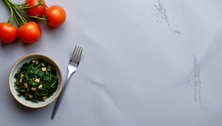 Fresh Ingredients for Healthy Meal Preparation Featuring Tomatoes and Spinach Salad in a Bowl with a Fork on a Textured Backgroundの素材