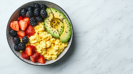 Colorful and Nutritious Breakfast Bowl with Scrambled Eggs, Fresh Strawberries, Blackberries, and Sliced Avocado on a Marble Surfaceの素材