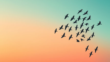 A serene sunset scene with a flock of birds flying across a gradient sky of soft orange and teal hues.の素材
