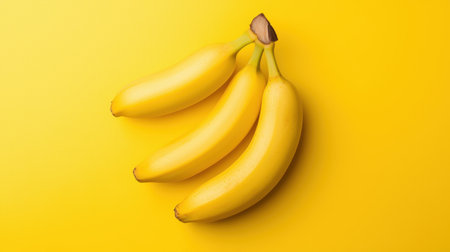 A vibrant image featuring three ripe bananas against a bright yellow background.の素材