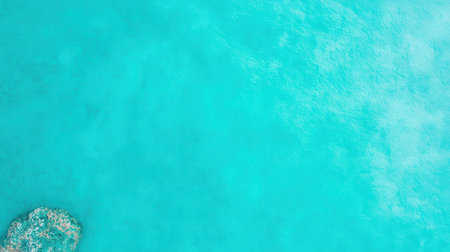 A serene view of clear turquoise water with a small rocky outcrop, evoking a sense of tranquility and natural beauty.の素材