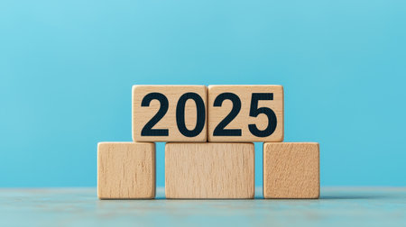 A simple wooden block display shows the year "2025" against a light blue background, symbolizing future plans and aspirations.の素材
