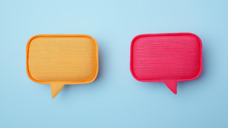 Two colorful speech bubble shapes in yellow and pink against a light blue background, representing communication and expression.の素材